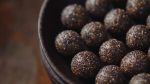 Close-up of churma ladoos coated with poppy seeds, arranged in a dark bowl