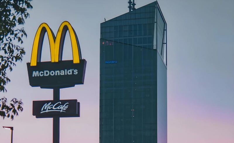 A McDonald's sign stands tall against a modern skyscraper