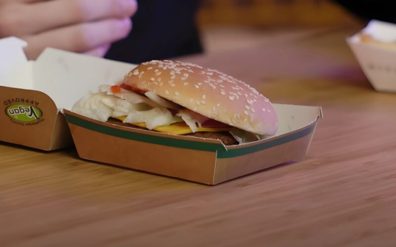 A vegan burger, nestled in a disposable cardboard container