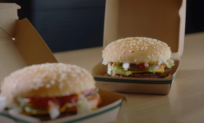 Two freshly prepared hamburgers, nestled in their paper containers