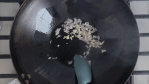 Minced Garlic and Diced Onion Sizzling in A Hot Wok with A Silicone Spatula Stirring Them