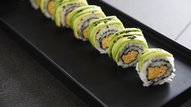 A Row of Beautifully Plated Vegetarian Sushi Rolls Topped with Avocado