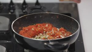 Chopped Nuts Sprinkled Over a Pan of Cooking Carrot Beetroot Halwa on A Stovetop