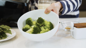 A Person Holding a White Bowl Filled with Freshly Blanched Broccoli Florets