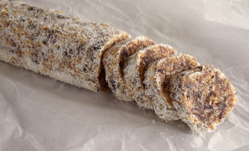 A sliced log of date and nut roll coated in shredded coconut