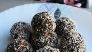 A Plate of Carrot Beetroot Laddoos Coated in Grated Coconut, Stacked and Ready to Set