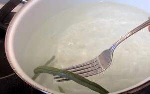 Fresh green beans gently submerged in simmering water