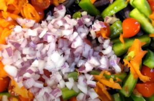 Diced red onion and other vegetables combine in a bowl