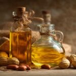 Bottles of peanut oil and vegetable oil placed beside raw peanuts on a rustic table