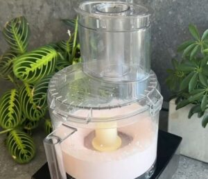 A food processor filled with a vibrant pink liquid