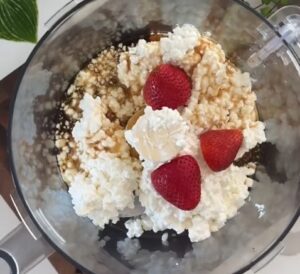 Blender filled with fluffy whipped cream and fresh strawberries