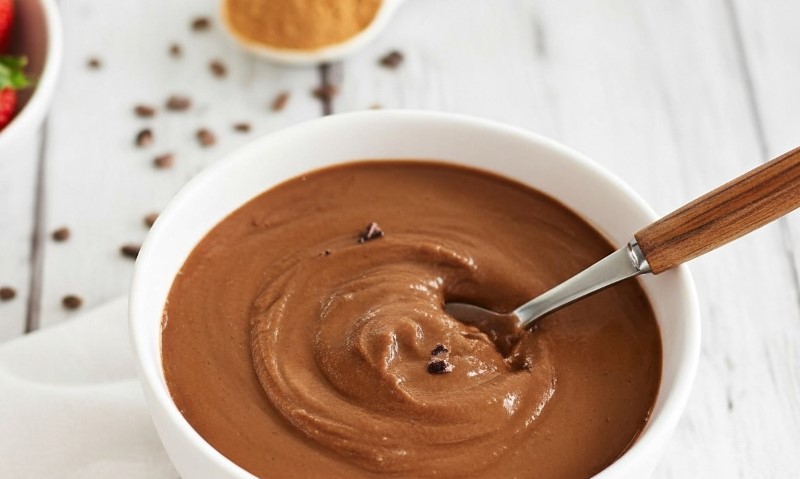 Chocolate pudding in a bowl with a silver spoon resting beside it