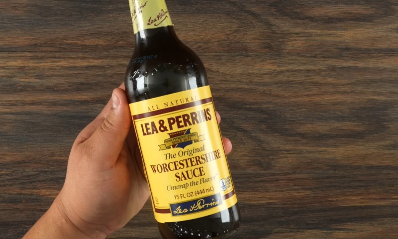 A hand holding a bottle of Worcestershire Sauce
