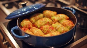 A pot filled with cabbage rolls simmering in tomato sauce on a stovetop