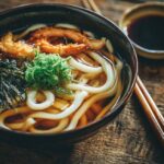 Bowl of udon noodle soup with broth, shrimp, seaweed, and green onions