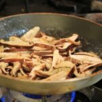Shiitake mushrooms sauté in a hot pan with enough space to brown evenly without steaming