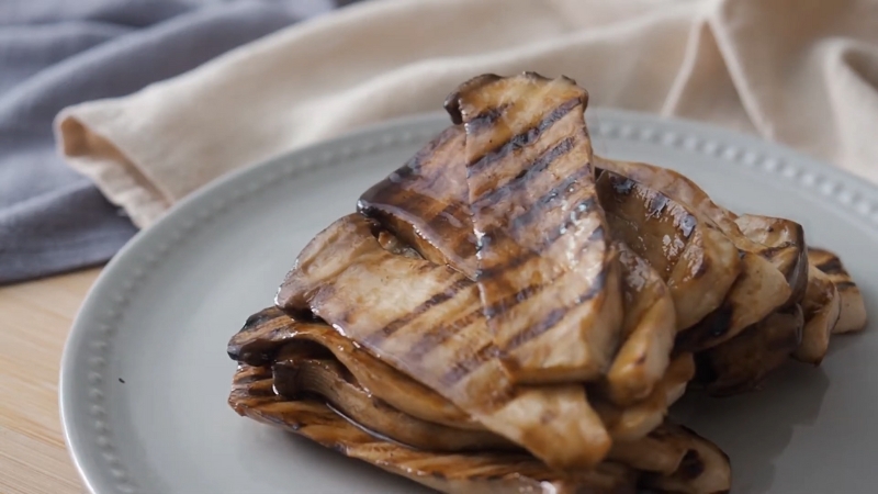 Grilled king oyster mushroom slabs with clear grill marks stacked on a plate