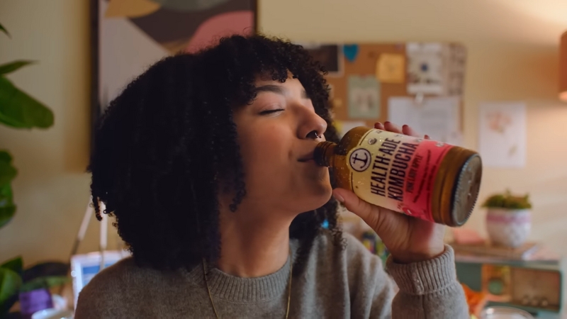 A woman drinks a bottle of Health-Ade Kombucha at home