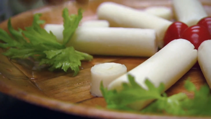 Whole hearts of palm resting on a board with herbs, just drained and ready for prep