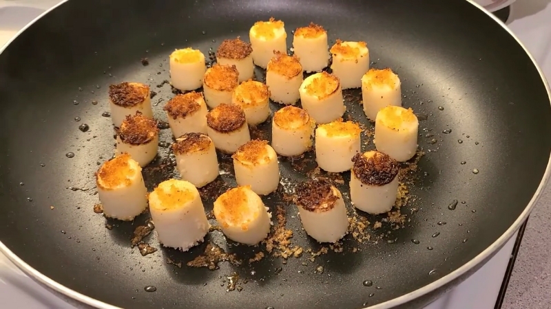 Hearts of palm searing in a hot pan with browned edges and a golden surface