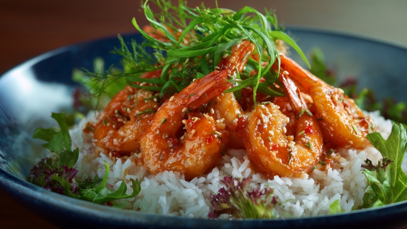 Plant-based shrimp served over rice with glossy sauce, sesame seeds, and fresh herbs