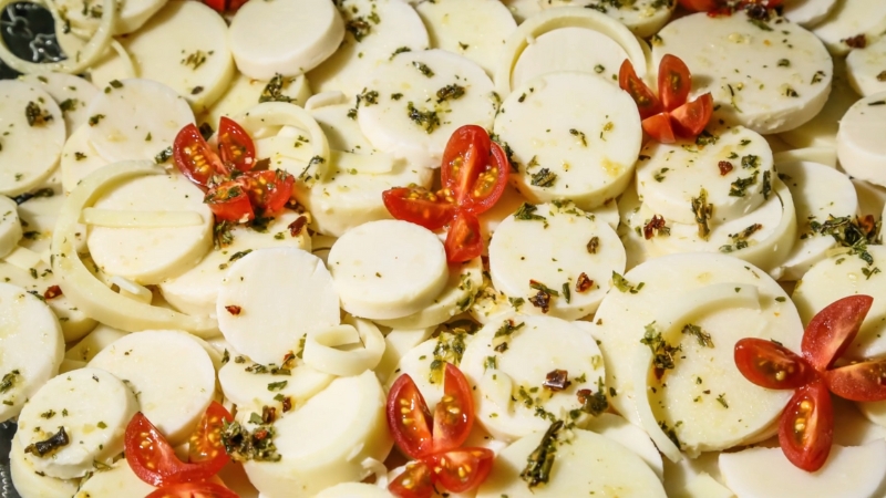 Sliced hearts of palm served cold with herbs, oil, and cherry tomatoes on a platter