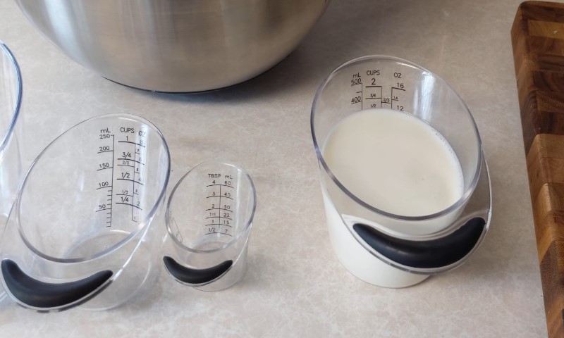 Three varying-sized clear measuring cups with black handles on a kitchen counter